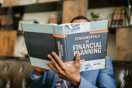 Free Person Reading a Book About Fundamentals of Financial Planning Stock Photo